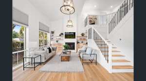 white open living space with grand staircase, chandeliers, and sofas
